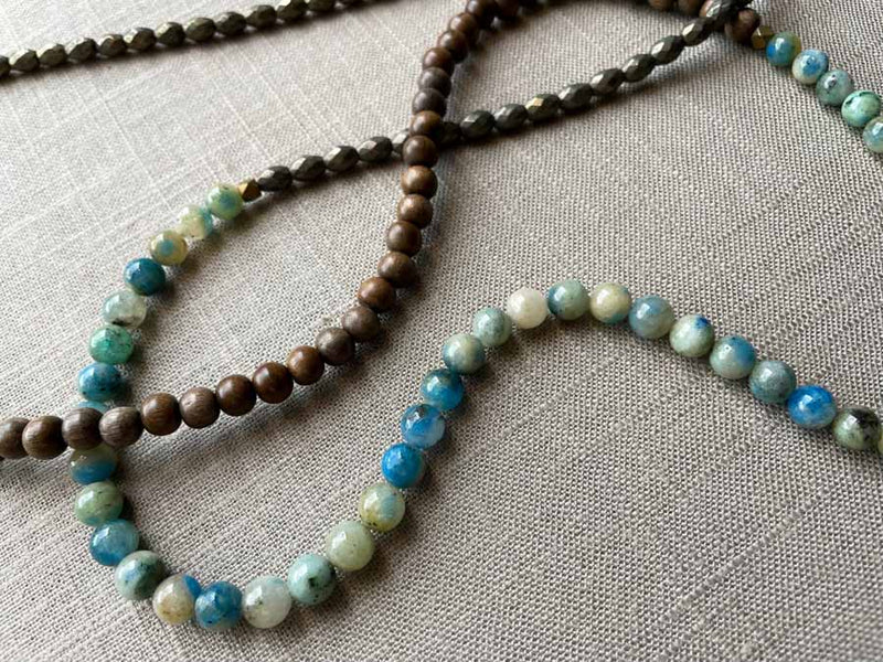 closeup of gemstone bead necklace comprising blue azurite, dark grey pyrite and exotic wood