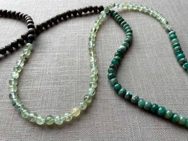 closeup of gemstone bead necklace comprising green prehnite, teal aventurine and exotic wood