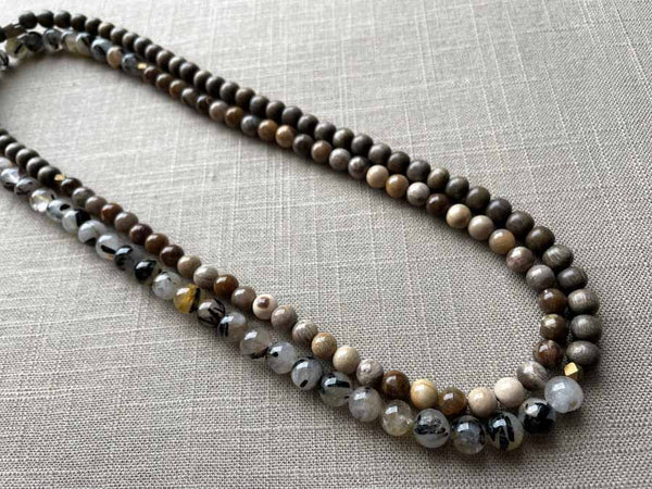 top view of gemstone bead necklace comprising beige fossilized wood, black and white tourmalated quartz and exotic wood