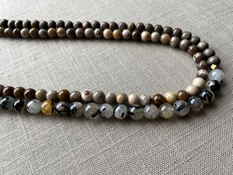 side view of gemstone bead necklace comprising beige fossilized wood, black and white tourmalated quartz and exotic wood