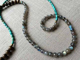 closeup of gemstone bead necklace comprising blue labradorite, barrel turquoise and exotic wood