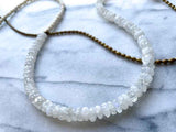 closeup of gemstone bead necklace comprising white moonstone, conch shell and bronze