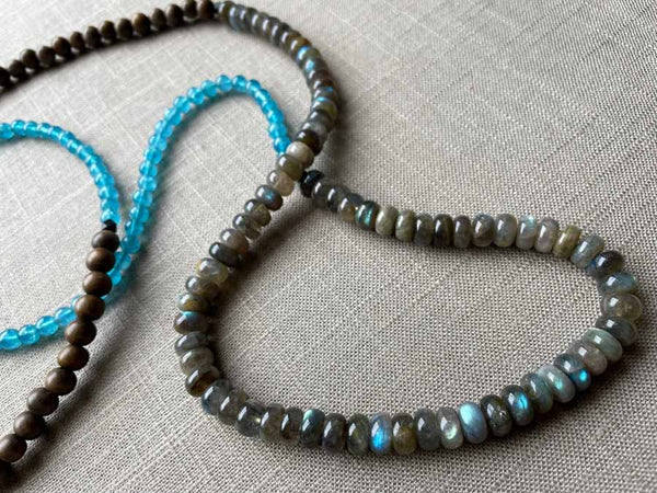 closeup of gemstone bead necklace comprising blue apatite, blue labradorite and exotic wood