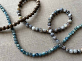 closeup of gemstone bead necklace comprising blue kyanite, neutral dendritic opal and exotic wood