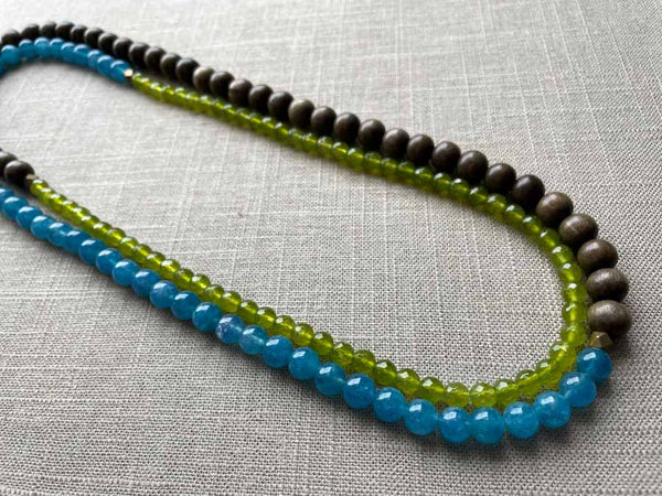 top view of gemstone bead necklace comprising blue apatite, green peridot and exotic wood