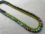 top view of gemstone bead necklace comprising blue chrysoprase, green peridot and exotic wood