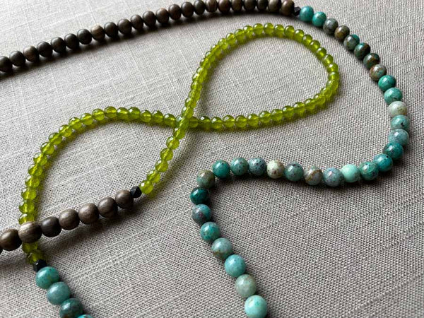 closeup of gemstone bead necklace comprising blue chrysoprase, green peridot and exotic wood