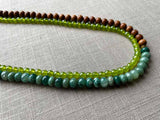 side view of gemstone bead necklace comprising teal aventurine, green peridot and exotic wood