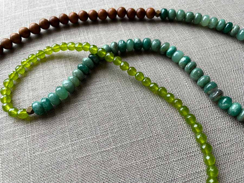 closeup of gemstone bead necklace comprising teal aventurine, green peridot and exotic wood