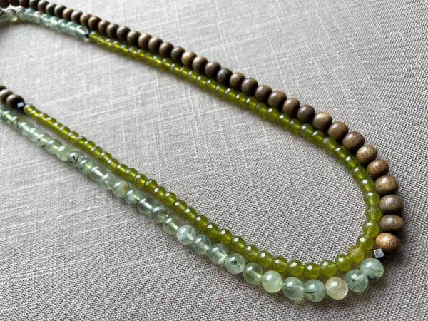 top view of gemstone bead necklace comprising green prehnite, green peridot and exotic wood