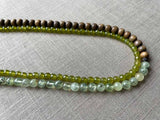 side view of gemstone bead necklace comprising green prehnite, green peridot and exotic wood