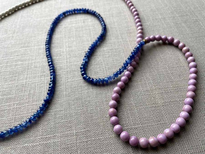 closeup of gemstone bead necklace comprising purple phosphosiderite, blue sapphire and white turquoise