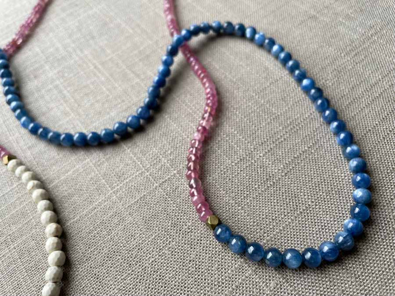 closeup of gemstone bead necklace comprising blue kyanite, pink sapphire and white turquoise