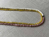 side view of gemstone bead necklace comprising pink strawberry quartz, yellow sapphire and white turquoise