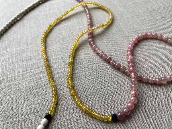 closeup of gemstone bead necklace comprising pink strawberry quartz, yellow sapphire and white turquoise