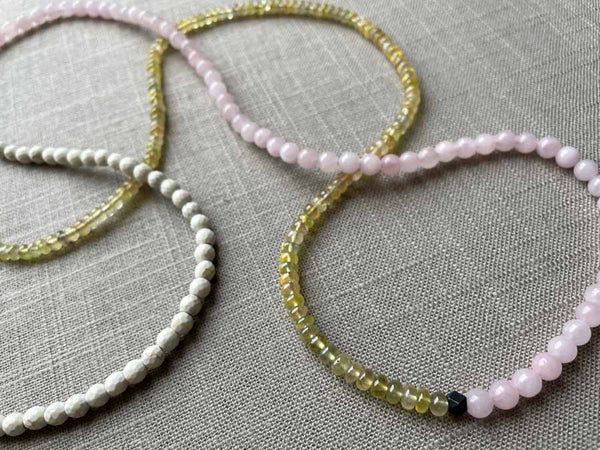 closeup of gemstone bead necklace comprising pink rose quartz, yellow sapphire and white turquoise