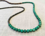 closeup of gemstone bead necklace comprising turquoise, dark grey pyrite and exotic wood