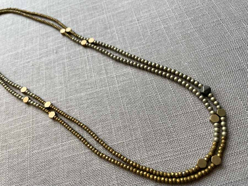 top view of gemstone bead necklace comprising gold hematite and bronze hex accents