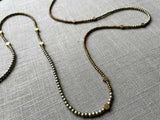 closeup of gemstone bead necklace comprising gold hematite and bronze hex accents