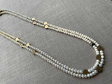 top view of gemstone bead necklace comprising white pearl, white conch shell and bronze dot accents