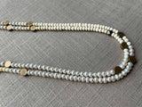 side view of gemstone bead necklace comprising white pearl, white conch shell and bronze dot accents