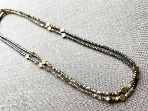 top view of gemstone bead necklace comprising black Tahitian shell, dark grey pyrite and bronze dot accents