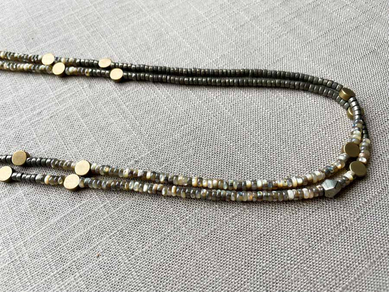 side view of gemstone bead necklace comprising black Tahitian shell, dark grey pyrite and bronze dot accents