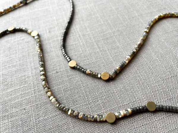 closeup of gemstone bead necklace comprising black Tahitian shell, dark grey pyrite and bronze dot accents