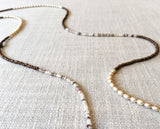 closeup of gemstone bead necklace comprising cream pearl, dark bronze hematite and neutral shell