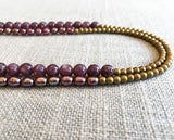 side view of gemstone bead necklace comprising pink pearl, gold hematite and dark pink charoite