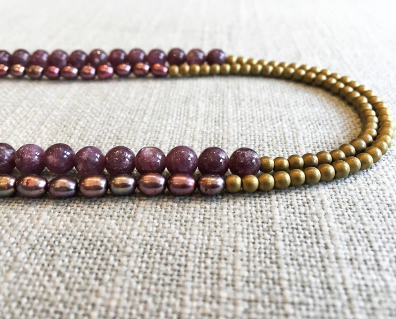 side view of gemstone bead necklace comprising pink pearl, gold hematite and dark pink charoite