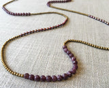 closeup of gemstone bead necklace comprising pink pearl, gold hematite and dark pink charoite