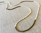 closeup of gemstone bead necklace comprising white pearl, gold hematite and white moonstone