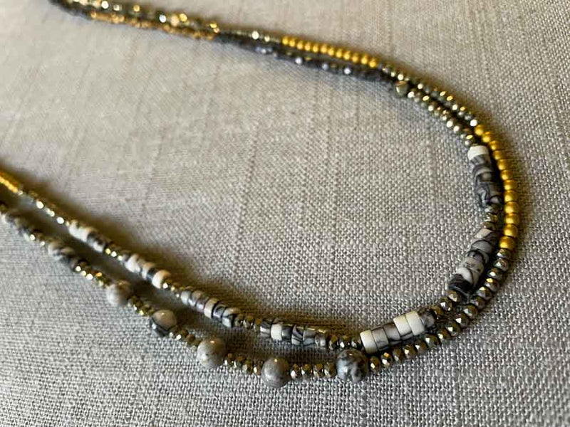 side viewof gemstone bead necklace comprising black and white feldspar, raw pyrite, dark bronze and gold hematite