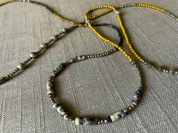 closeupof gemstone bead necklace comprising black and white feldspar, raw pyrite, dark bronze and gold hematite