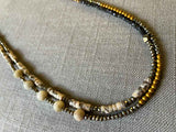 side view of gemstone bead necklace comprising neutral feldspar, raw pyrite, dark bronze and gold hematite