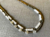 side view of gemstone bead necklace comprising white moonstone, white quartz, raw pyrite, bronze and gold hematite