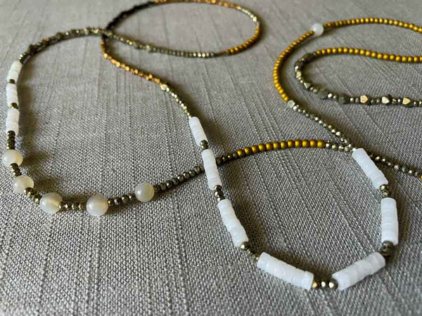 closeup of gemstone bead necklace comprising white moonstone, white quartz, raw pyrite, dark bronze and gold hematite