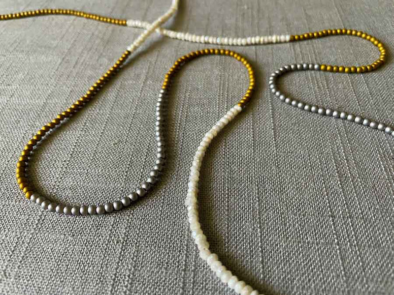 closeup of gemstone bead necklace comprising white moonstone, silver and gold hematite