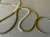 closeup of gemstone bead necklace comprising white moonstone, silver and gold hematite