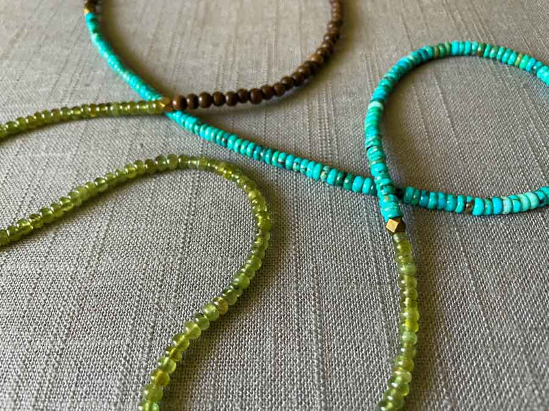 closeup of gemstone bead necklace comprising turquoise, green sapphire and exotic wood