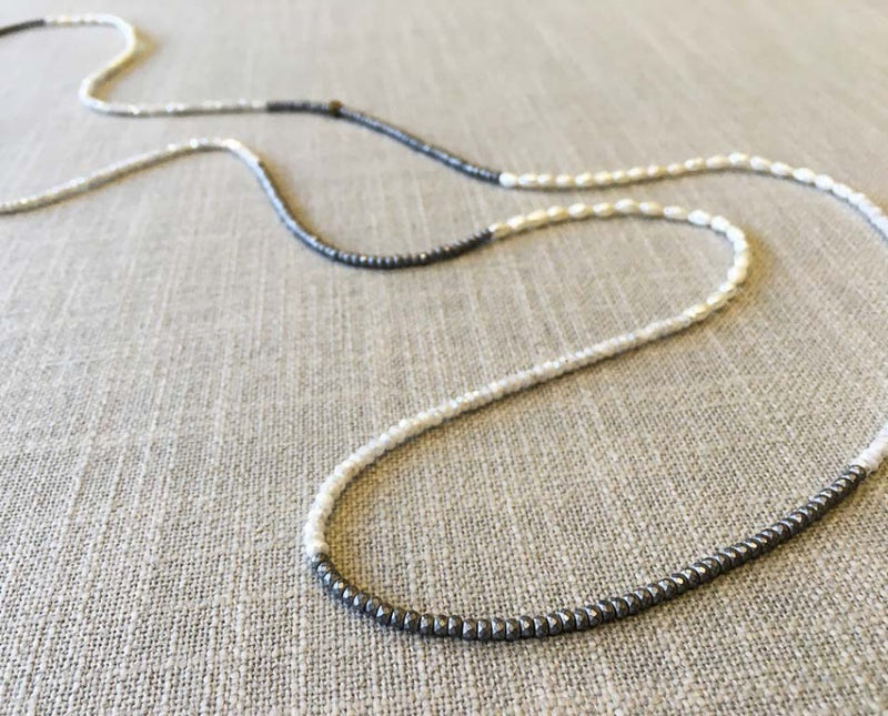 closeup of gemstone bead necklace comprising white pearl, silver hematite and white moonstone