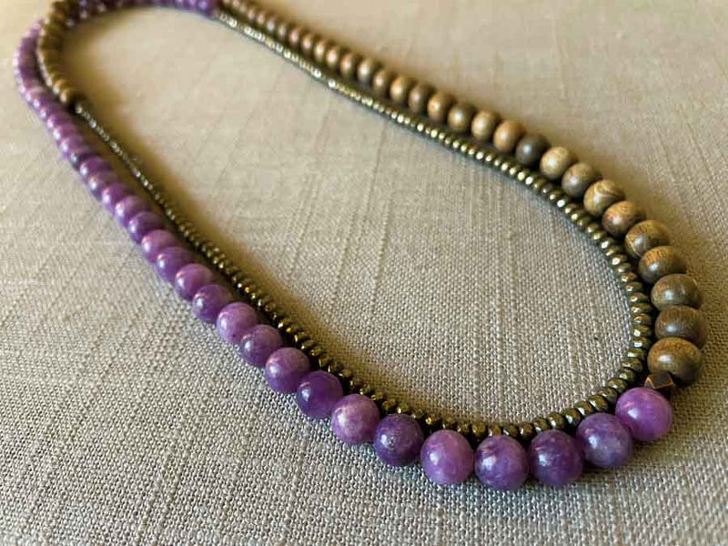 top view of gemstone bead necklace comprising purple lepidolite, dark grey pyrite and exotic wood