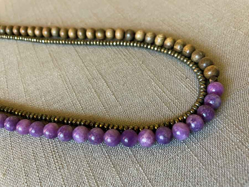 side view of gemstone bead necklace comprising purple lepidolite, dark grey pyrite and exotic wood