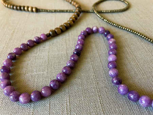 closeup of gemstone bead necklace comprising purple lepidolite, dark grey pyrite and exotic wood