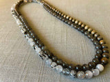 top view of gemstone bead necklace comprising black and white tourmalated quartz, grey moonstone and exotic wood