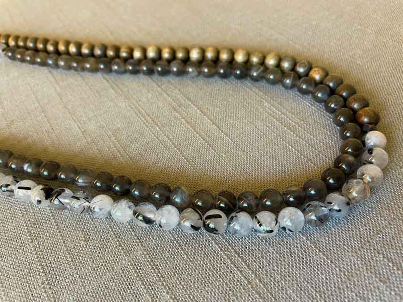 side view of gemstone bead necklace comprising black and white tourmalated quartz, grey moonstone and exotic wood