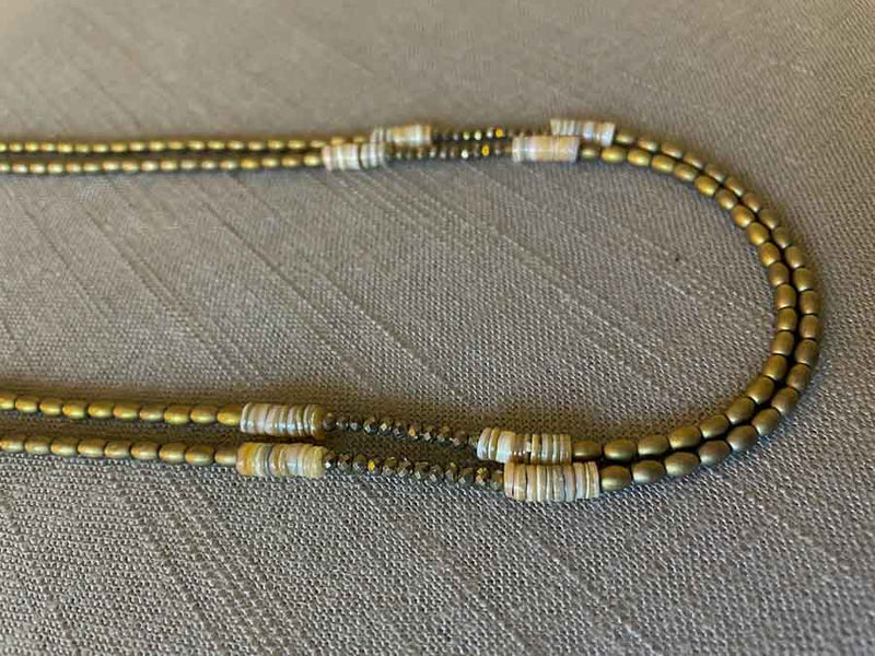 side view of gemstone bead necklace comprising neutral shell, light gold hematite and golden pyrite