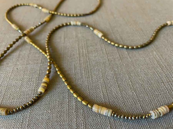 closeup of gemstone bead necklace comprising neutral shell, light gold hematite and golden pyrite