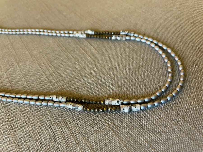 side view of gemstone bead necklace comprising black and white feldspar, silver hematite and dark grey pyrite